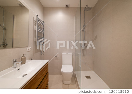 Modern bathroom with glass shower partition, white toilet, large mirror and wood vanity unit 126318910