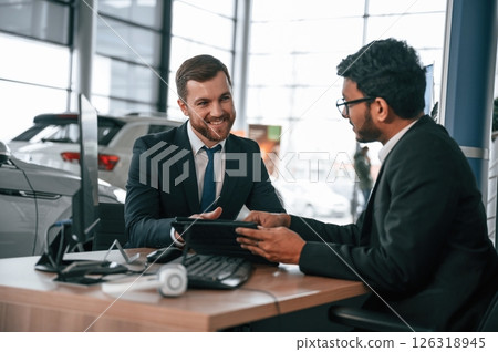 Using modern technology, graphic tablet, pc. Two businessmen are working together in the car showroom Using modern technology, graphic tablet, pc. Two businessmen are working together in the car showroom 126318945