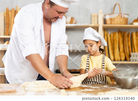 Little daughter and father make dough together in bakery kitchen 126319140
