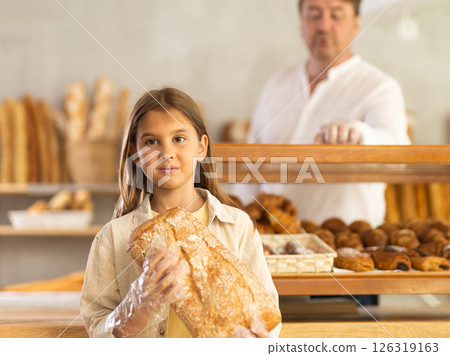 Girl in bakery chooses bread, considers various product options. 126319163