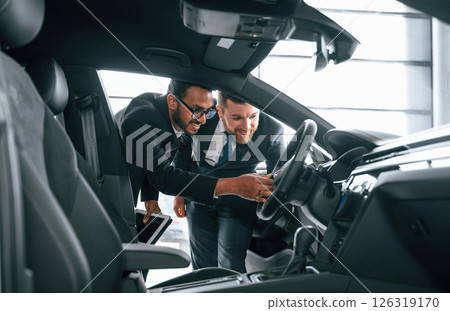 Man showing automobile interior to the customer 126319170