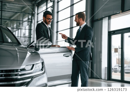Business partners. Man is consulting the customer in the car showroom Business partners. Man is consulting the customer in the car showroom 126319173