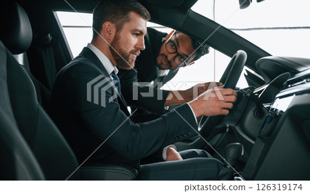 Man showing automobile interior to the customer 126319174