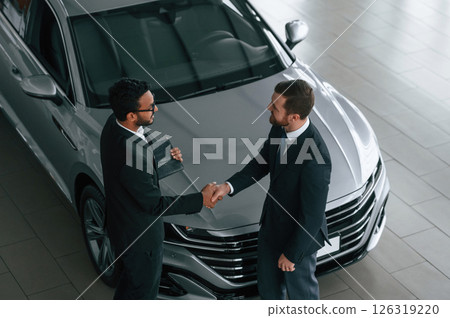 Doing handshake. Two businessmen are working together in the car showroom 126319220