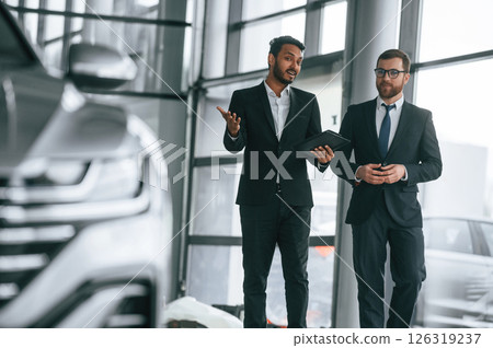 Talking about automobile. Man is consulting the customer in the car showroom Talking about automobile. Man is consulting the customer in the car showroom 126319237