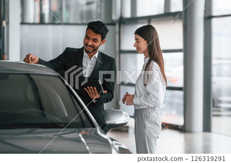 Man in formal clothes is consulting woman about the automobile in the car dealership 126319291