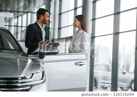 Man in formal clothes is consulting woman about the automobile in the car dealership Man in formal clothes is consulting woman about the automobile in the car dealership 126319294