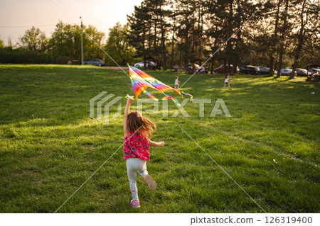 Children joyfully flying colorful kites in a sunny park 126319400