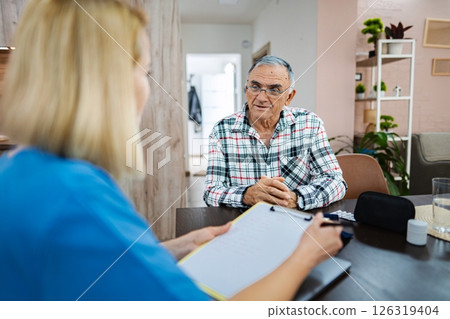 Elderly man chats thoughtfully with caregiver Elderly man chats thoughtfully with caregiver 126319404