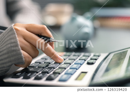 Finance bank tax expense accounting budget money businessman hand use calculator Financial calculate accountant close up calculator with graph chart write office desk Business expense analysis saving 126319420