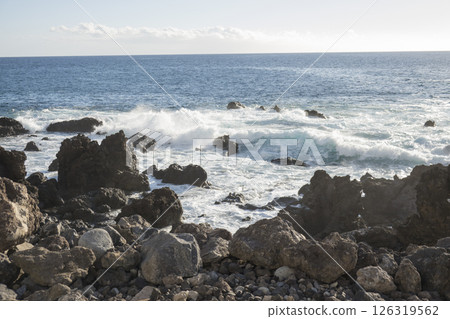 Waves Crashing Against black Lava Rocks on a Tropical Coast, water splashing at canary island Tenerife Waves Crashing Against black Lava Rocks on a Tropical Coast, water splashing at canary island Tenerife 126319562