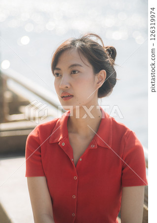 Young southeast asian woman entrepreneur and small business owner working remote as businesswoman outdoors with natural light and calm emotional expression 126319974