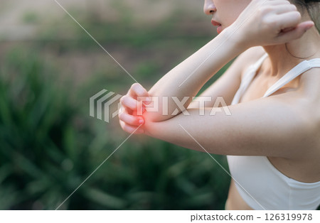Southeast asian female teen experiencing pain during exercise while jogging running in public park, highlighting sport health concerns and discomfort in elbow area, pain in exercise concept. Southeast asian female teen experiencing pain during exercise while jogging running in public park, highlighting sport health concerns and discomfort in elbow area, pain in exercise concept. 126319978