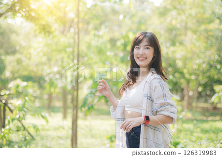 Southeast asian female young woman enjoying refreshing deep breath in public park expressing wellness and embracing healthy lifestyle in sunlight. Asian woman smiling with happiness and relaxation Southeast asian female young woman enjoying refreshing deep breath in public park expressing wellness and embracing healthy lifestyle in sunlight. Asian woman smiling with happiness and relaxation 126319983