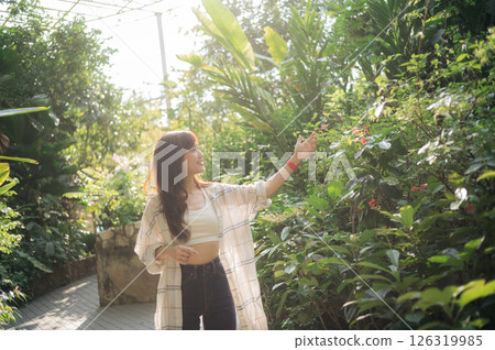 Southeast asian young female woman enjoying refreshing deep breath in public park surrounded by lush greenery expressing wellness and healthy lifestyle. woman in casual attire enjoys walk in garden Southeast asian young female woman enjoying refreshing deep breath in public park surrounded by lush greenery expressing wellness and healthy lifestyle. woman in casual attire enjoys walk in garden 126319985