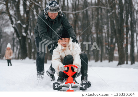 Sled ride. Mother and father is with daughter have walk outdoors at the winter season Sled ride. Mother and father is with daughter have walk outdoors at the winter season 126320104