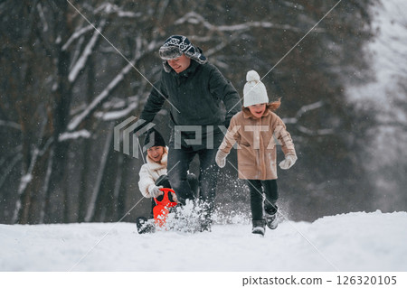 Sled ride. Mother and father is with daughter have walk outdoors at the winter season 126320105