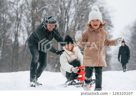 Woman is on sled ride. Happy family is outdoors, enjoying snow time at winter together 126320107