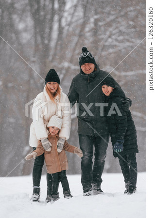Front view. Happy family is outdoors, enjoying snow time at winter together Front view. Happy family is outdoors, enjoying snow time at winter together 126320160