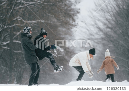 Playing snowballs. Happy family is outdoors, enjoying snow time at winter together Playing snowballs. Happy family is outdoors, enjoying snow time at winter together 126320183