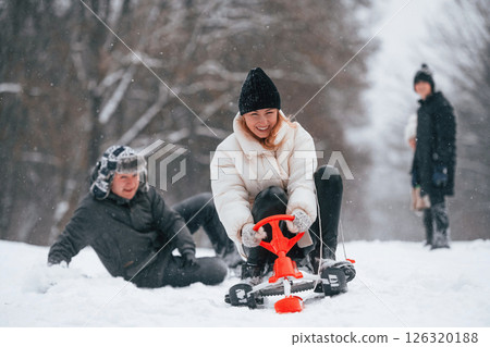 Woman is on sled ride. Happy family is outdoors, enjoying snow time at winter together Woman is on sled ride. Happy family is outdoors, enjoying snow time at winter together 126320188