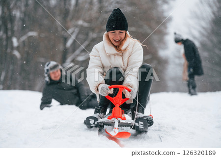 Woman is on sled ride. Happy family is outdoors, enjoying snow time at winter together Woman is on sled ride. Happy family is outdoors, enjoying snow time at winter together 126320189