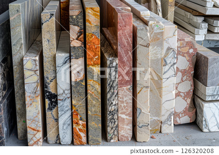 A collection of marble slabs in different shades and textures aligned in a stone workshop, highlighting the unique beauty of natural materials 126320208