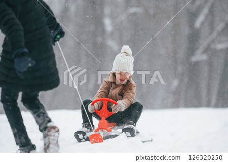 Brother with his sister is outdoors at winter season. Taking girl to a sled Brother with his sister is outdoors at winter season. Taking girl to a sled 126320250