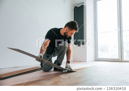 Fitting the planks. Man is installing new laminated wooden floor 126320410