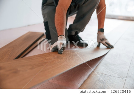Close up view. Man is installing new laminated wooden floor Close up view. Man is installing new laminated wooden floor 126320416