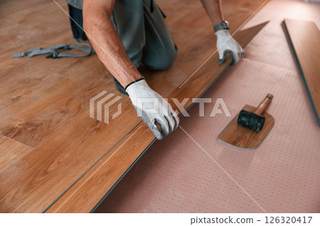 Close up view. Man is installing new laminated wooden floor Close up view. Man is installing new laminated wooden floor 126320417