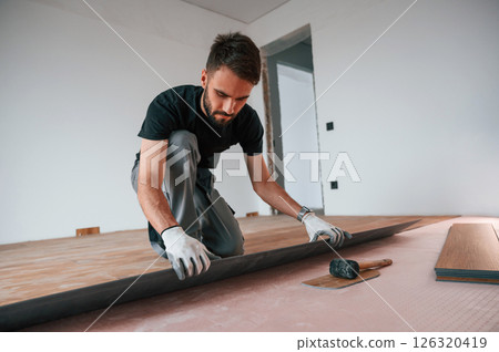 Hand work. Man is installing new laminated wooden floor 126320419