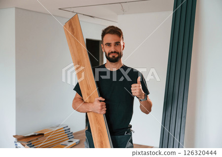 Holding the planks. Man is installing new laminated wooden floor Holding the planks. Man is installing new laminated wooden floor 126320444