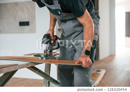 Cutting the planks. Man is installing new laminated wooden floor Cutting the planks. Man is installing new laminated wooden floor 126320454