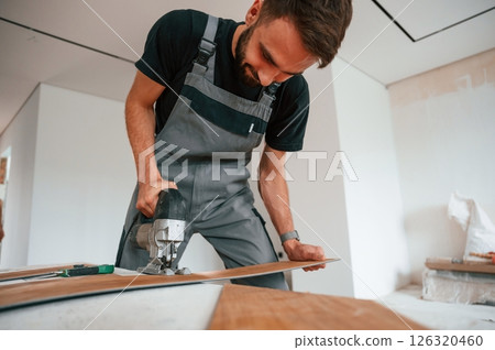 On the table. Cutting planks by the drill. Man is installing new laminated wooden floor 126320460
