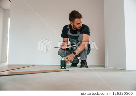 Laser leveler device. Man is installing new laminated wooden floor 126320500