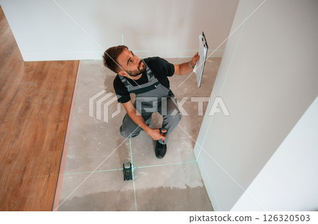 Top view. Man is installing new laminated wooden floor Top view. Man is installing new laminated wooden floor 126320503