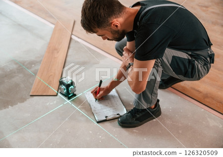 Using the leveler. Man is installing new laminated wooden floor Using the leveler. Man is installing new laminated wooden floor 126320509