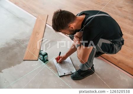 Using the leveler. Man is installing new laminated wooden floor Using the leveler. Man is installing new laminated wooden floor 126320538