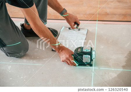 Using the leveler. Man is installing new laminated wooden floor Using the leveler. Man is installing new laminated wooden floor 126320540