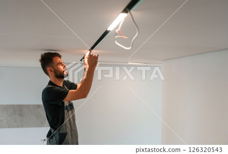 Man is working with lighting equipment indoors at domestic room 126320543