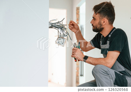 Close up view. Electrician is working with wires indoors in the room Close up view. Electrician is working with wires indoors in the room 126320568