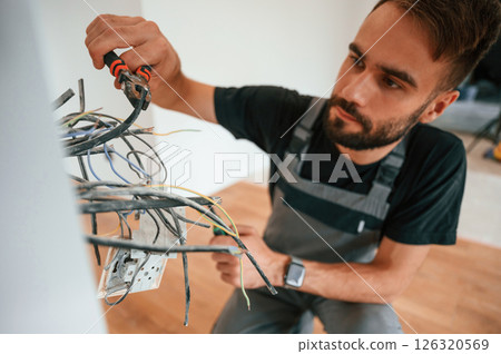Close up view. Electrician is working with wires indoors in the room 126320569