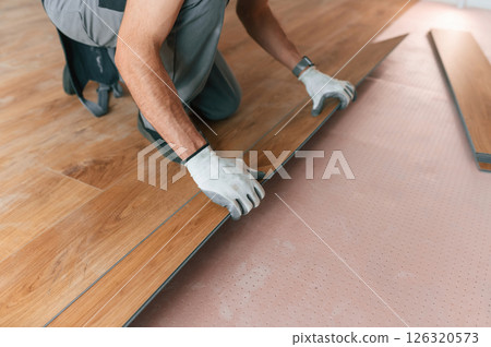 Man is installing new laminated wooden floor 126320573