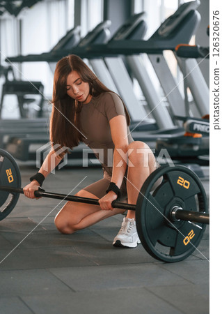 With barbell on the floor. Beautiful woman with sport body type is in the gym 126320676
