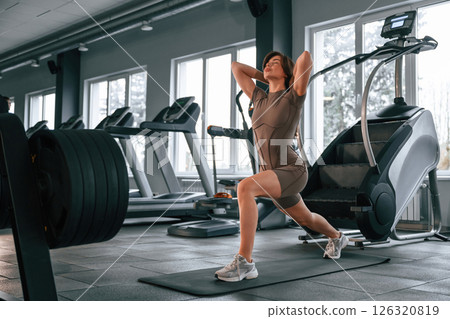 Doing squats. Beautiful woman with sport body type is in the gym Doing squats. Beautiful woman with sport body type is in the gym 126320819
