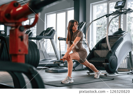 Doing squats. Beautiful woman with sport body type is in the gym Doing squats. Beautiful woman with sport body type is in the gym 126320820