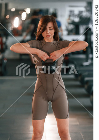 Lifting dumbbell. Beautiful woman with sport body type is in the gym 126320842