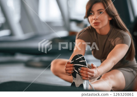 Stretching exercises. Beautiful woman with sport body type is in the gym Stretching exercises. Beautiful woman with sport body type is in the gym 126320861