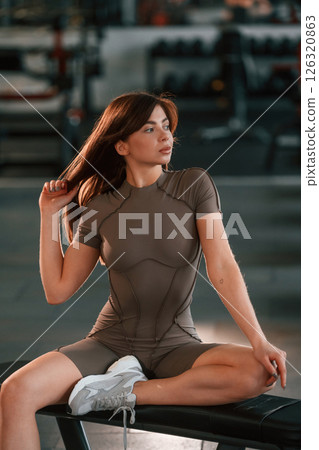 In fitness clothes, sitting and resting. Beautiful woman with sport body type is in the gym In fitness clothes, sitting and resting. Beautiful woman with sport body type is in the gym 126320863
